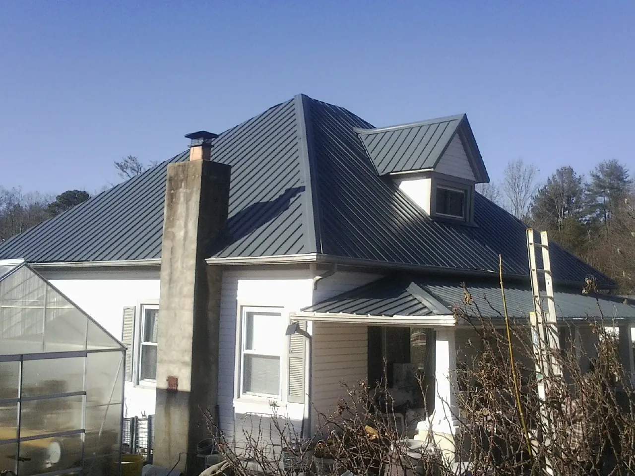 Dark blue standing seam metal roof on a white farmhouse with dormer — Slate & Tile Roof Repair by Roofing Brothers in French Gulch