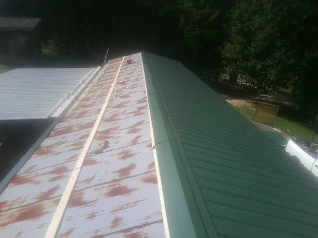 Old rusted panels beside newly installed green metal roofing — Wind Damage Roof Repair by Roofing Brothers in French Gulch