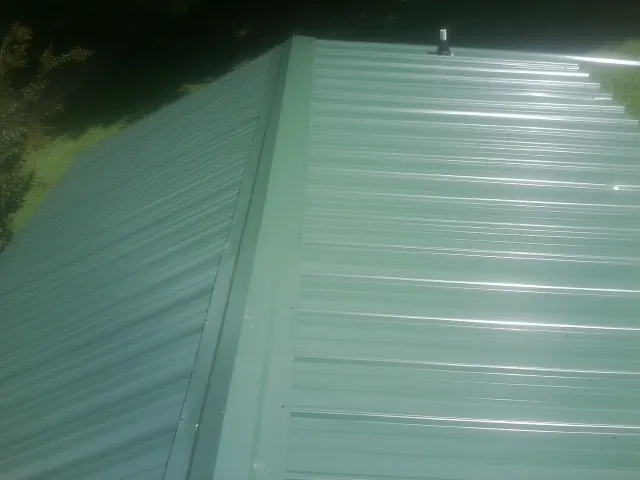 New green metal panels meeting at the ridge of a roof — Flat Roof Repair work by our crew in French Gulch