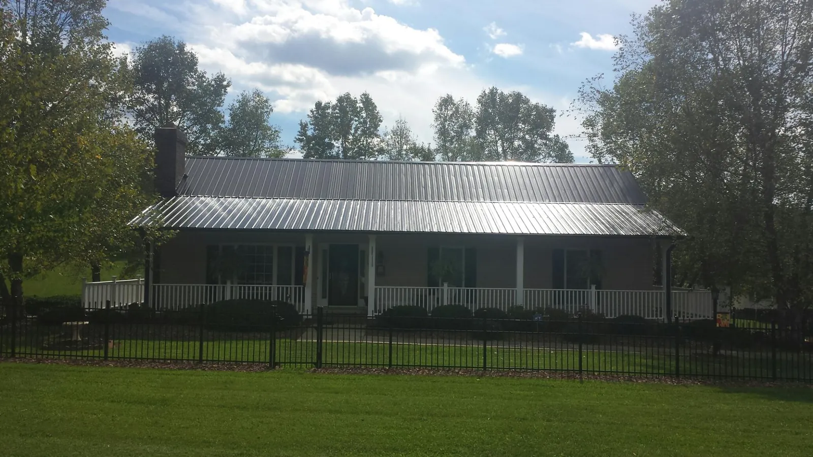 Gray metal roof on a brick ranch with a full width front porch — Gutter Guard Installation work by our crew in French Gulch